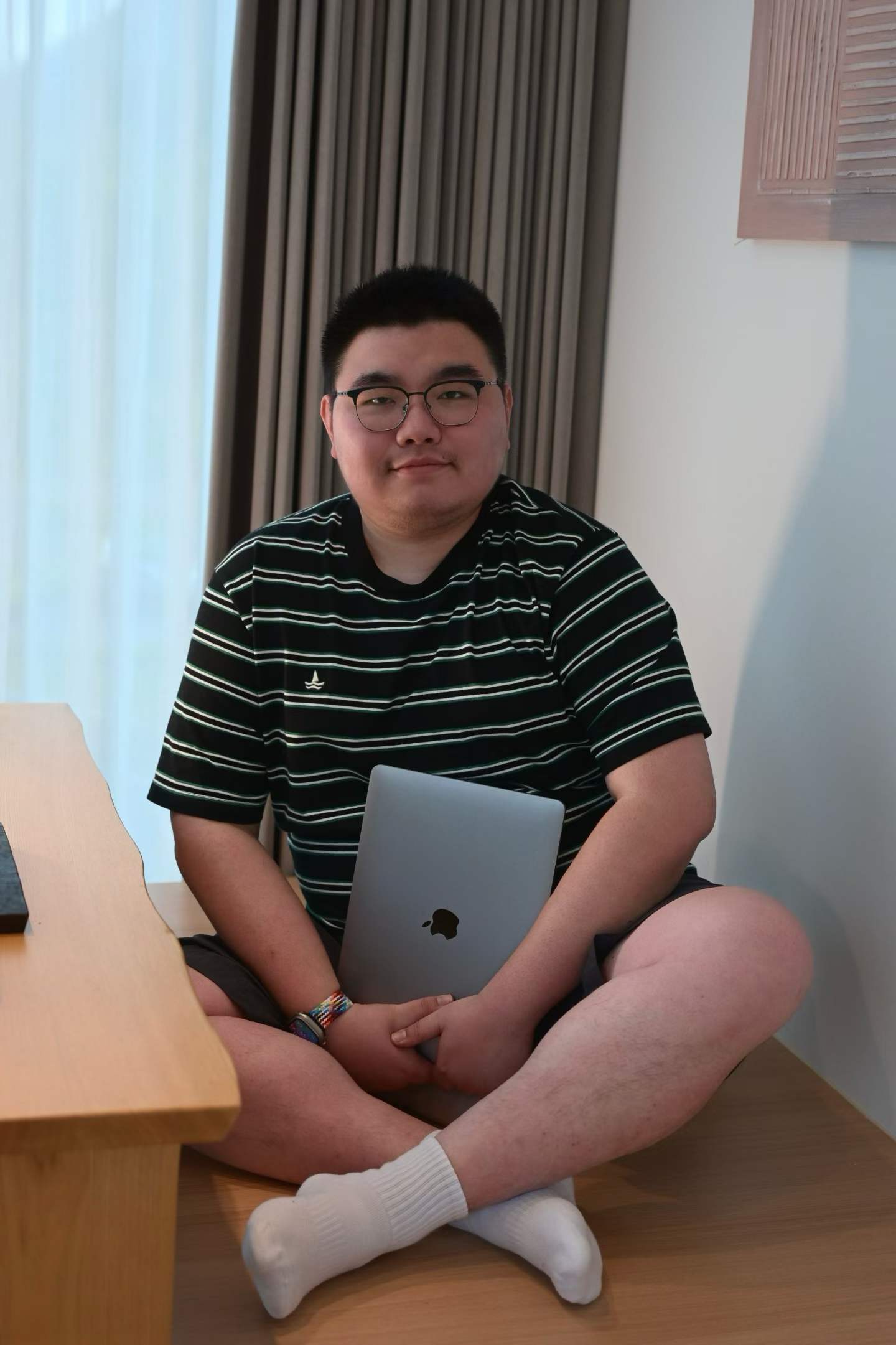 尹晗戴着眼镜，抱着笔记本电脑坐在窗边